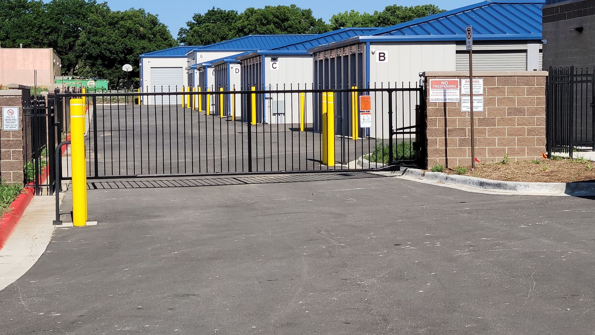 A fence built by Greater Western Fence with yellow poles is surrounding a parking lot.
