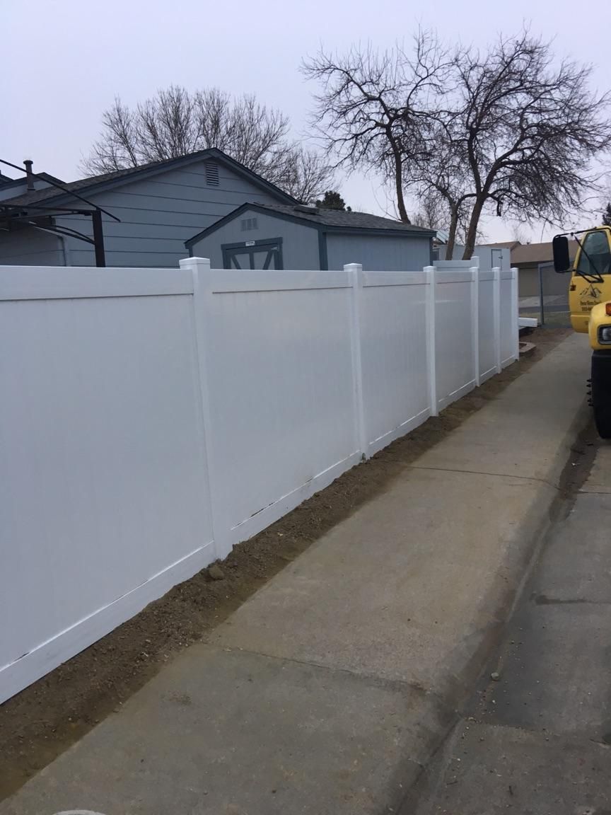 A white fence along a sidewalk next to a house.