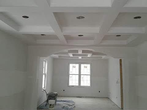 White room with decorative coffered ceiling, recessed lighting, and arched doorway. Unfinished construction.