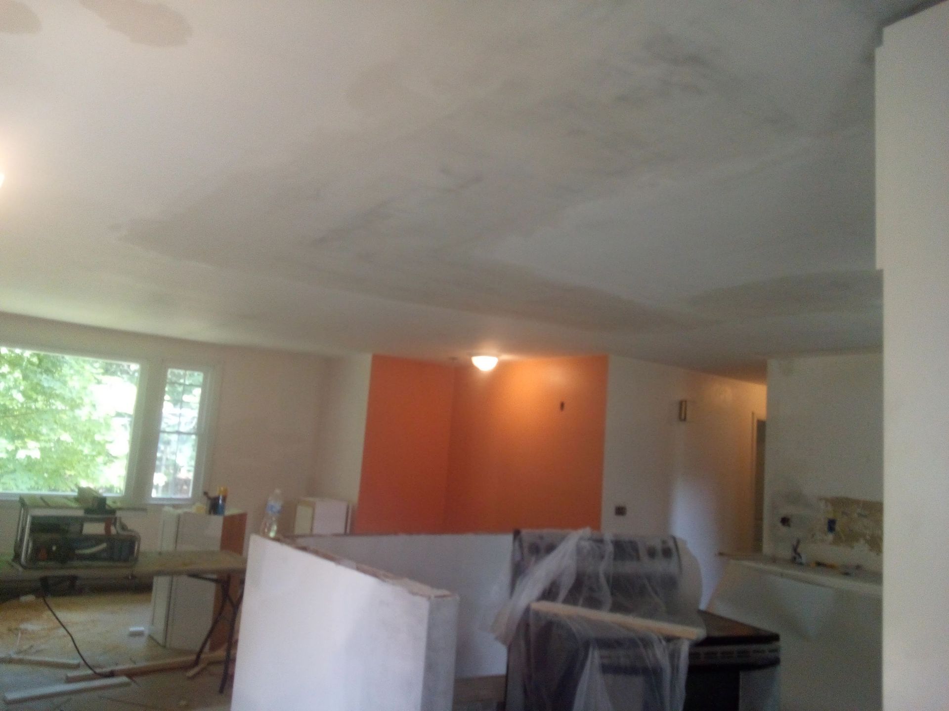 Renovation of interior space with white walls and ceiling, orange accent wall, and construction materials.