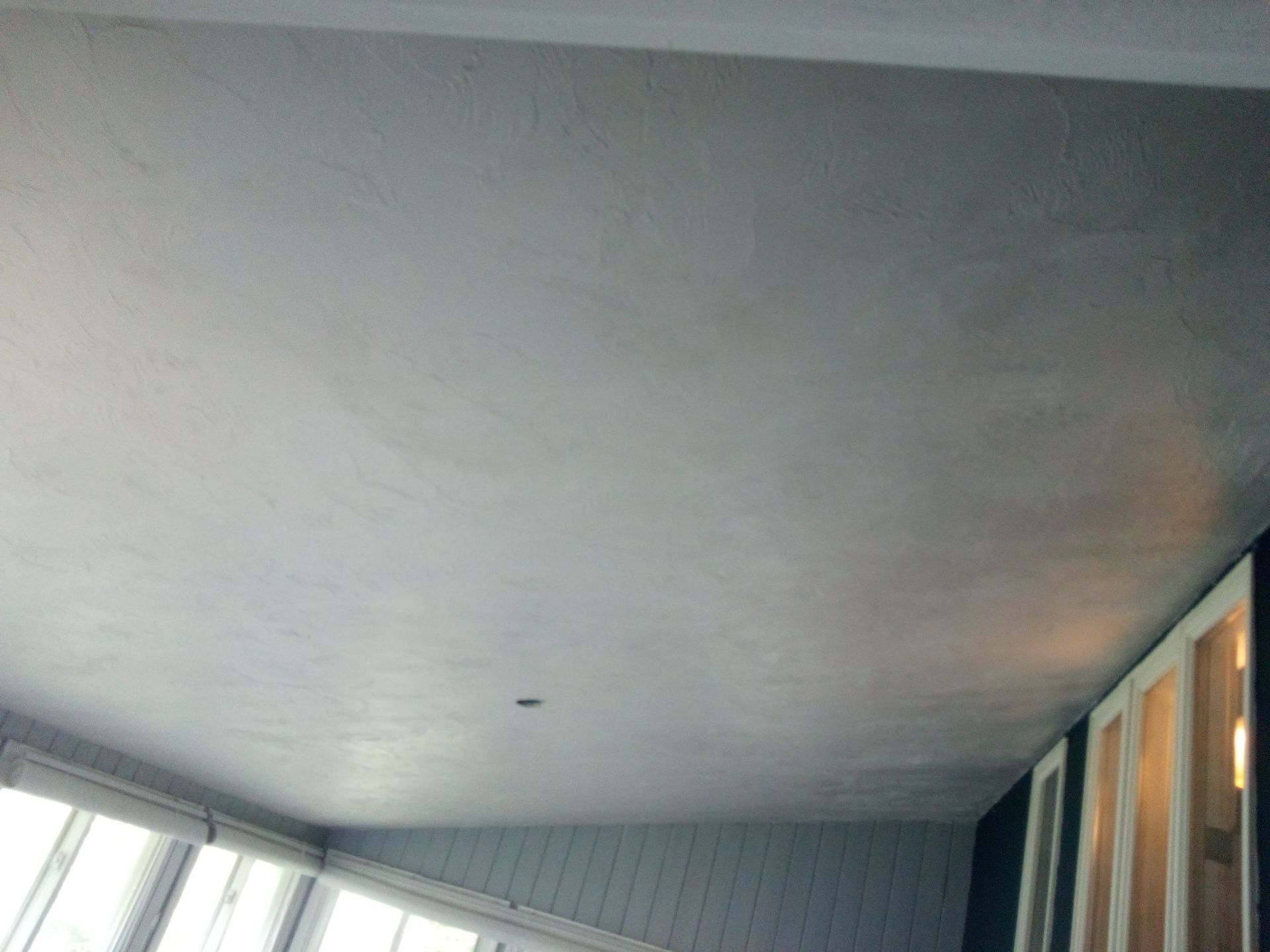 Gray ceiling with slight texture, bordering window frames and white trim.