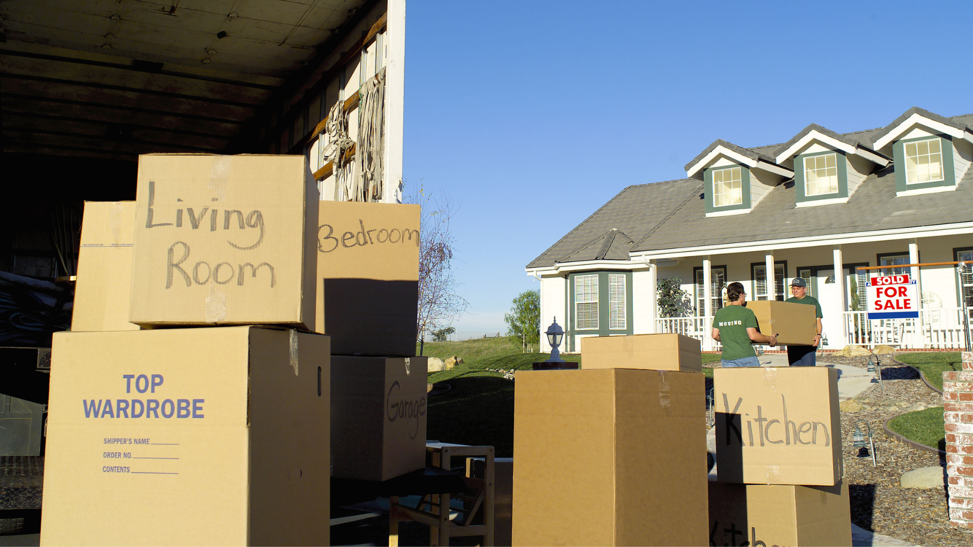 A professional mover helping to move large boxes in an office space while another mover adjusts furniture, highlighting teamwork during a commercial move.