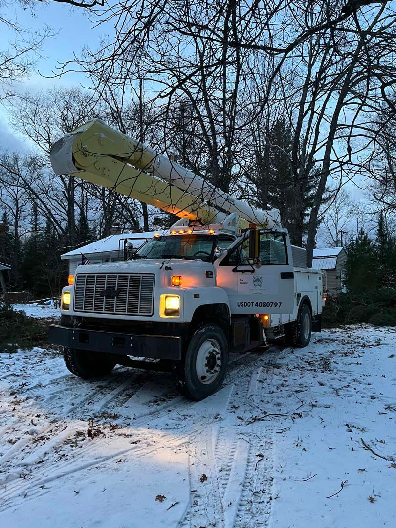 A white truck with a crane on top of it is parked in the snow.