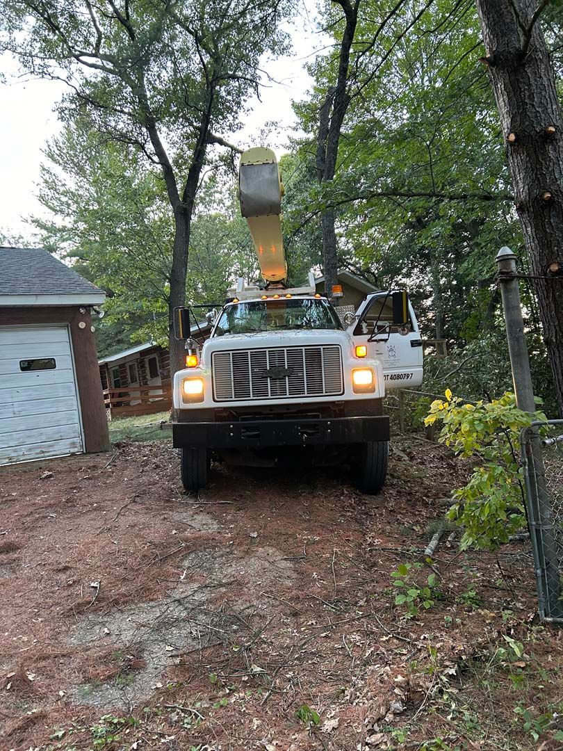 A white truck with a crane on top of it is parked in front of a garage.