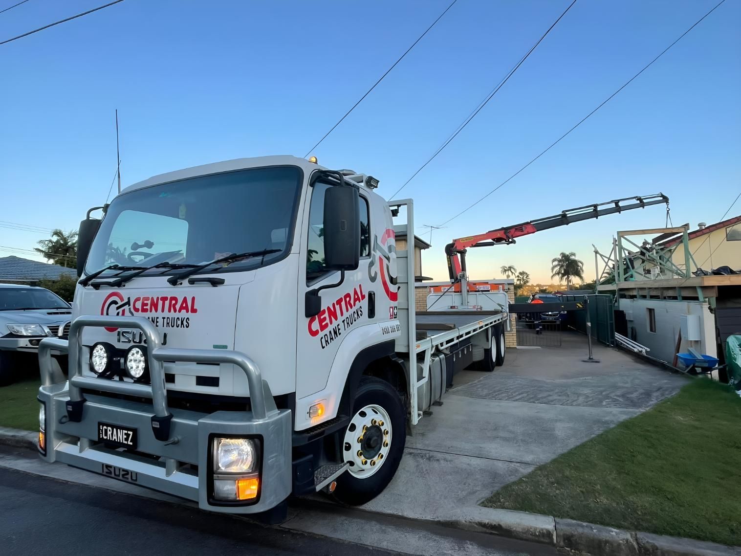 A Flatbed Truck With a Crane Attached to It is Parked in a Driveway — Central Crane Trucks In Gold Coast, QLD