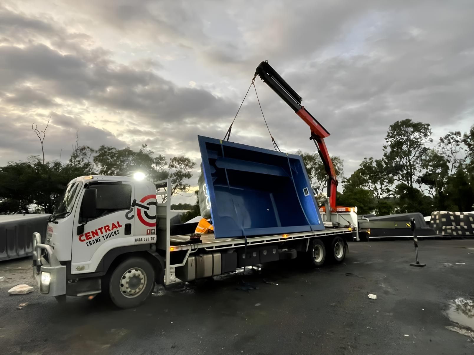 A Large Blue Swimming Pool is Being Lifted by a Crane on Top of a Truck — Central Crane Trucks In Gold Coast, QLD