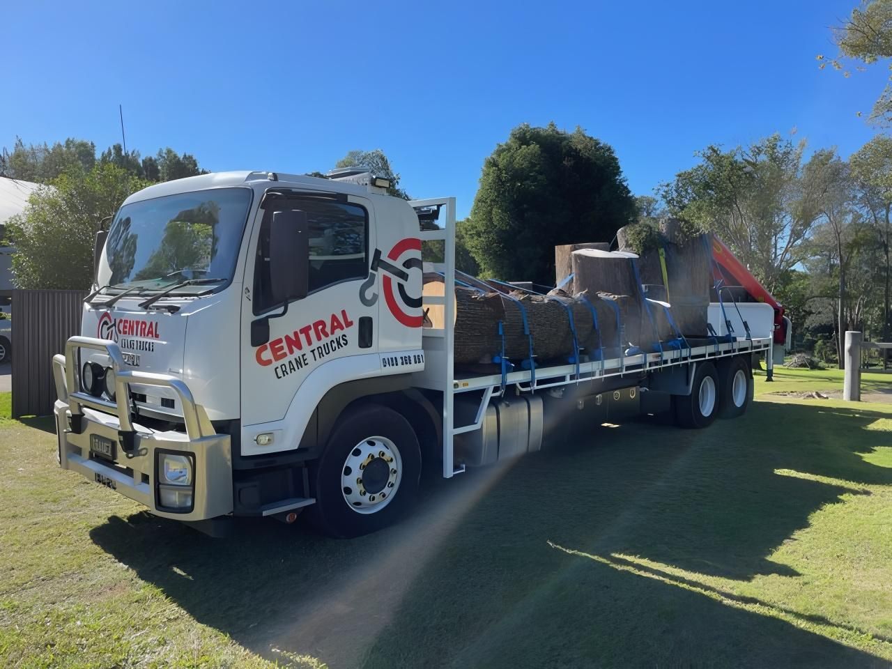 A White Truck With the Word Central on the Side is Parked in a Grassy Field — Central Crane Trucks In Stapylton, QLD