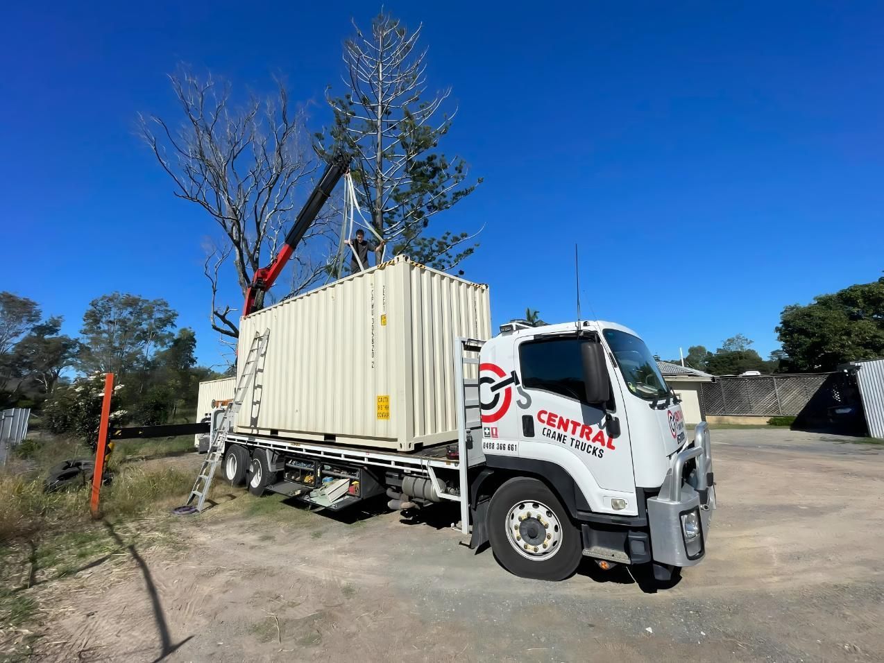 A Truck With a Crane Attached to It is Carrying a Shipping Container — Central Crane Trucks In Stapylton, QLD