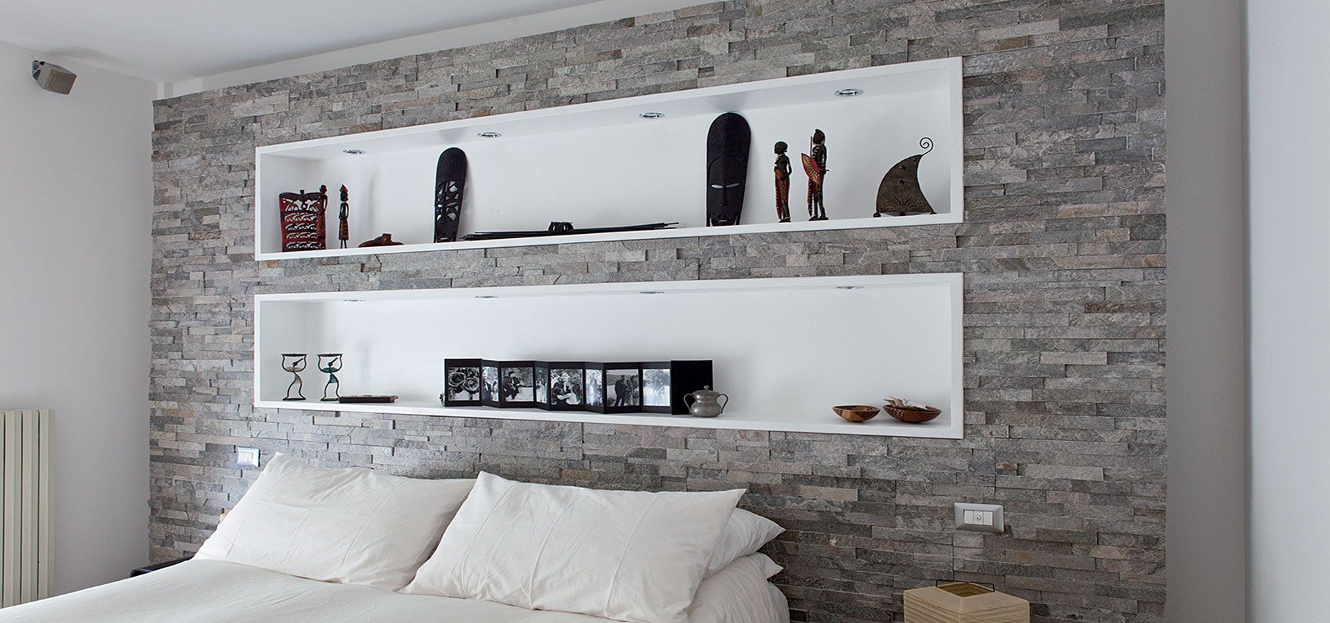 camera da letto con parete in pietra naturale con mensole incassate