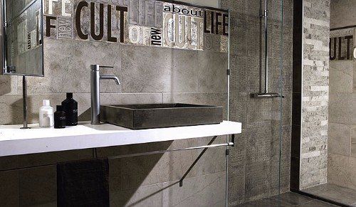 un bagno con un lavabo nero e i muri con le piastrelle a effetto pietra di color grigio