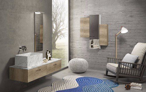 un bagno con un lavabo in marmo, uno specchio a muro e davanti una poltrona a dondolo