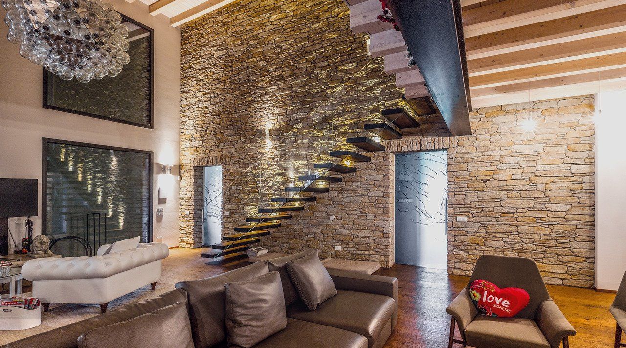 soggiorno elegante con divani in pelle, parete in pietra vera e pavimento in legno