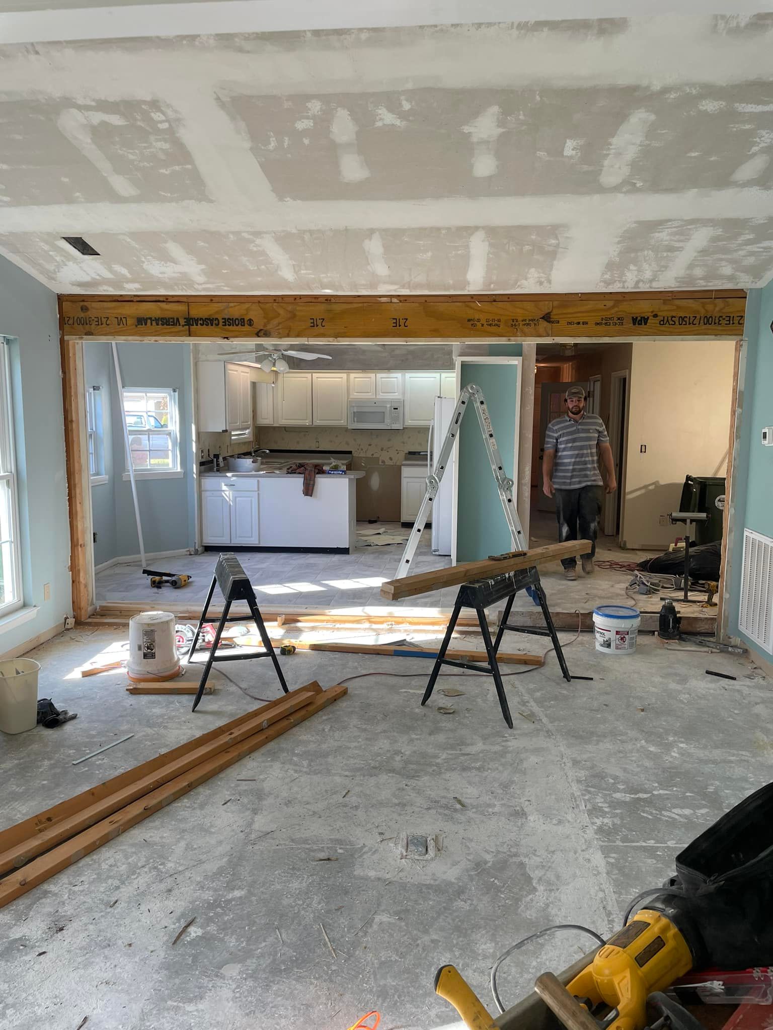 A house is being remodeled and a man is standing in the middle of the room.