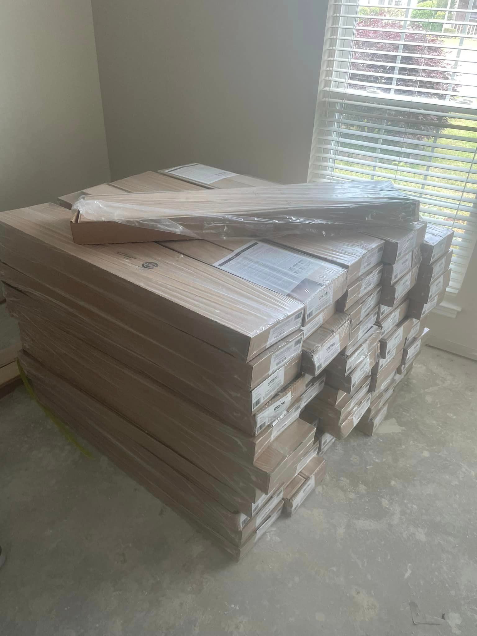 A stack of cardboard boxes sitting on top of each other in a room next to a window.