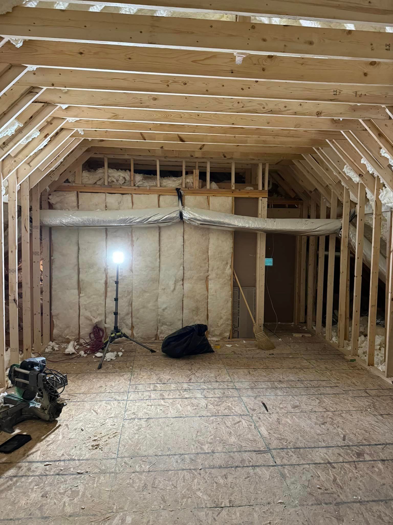A room with a lot of wooden beams and a light on the floor.