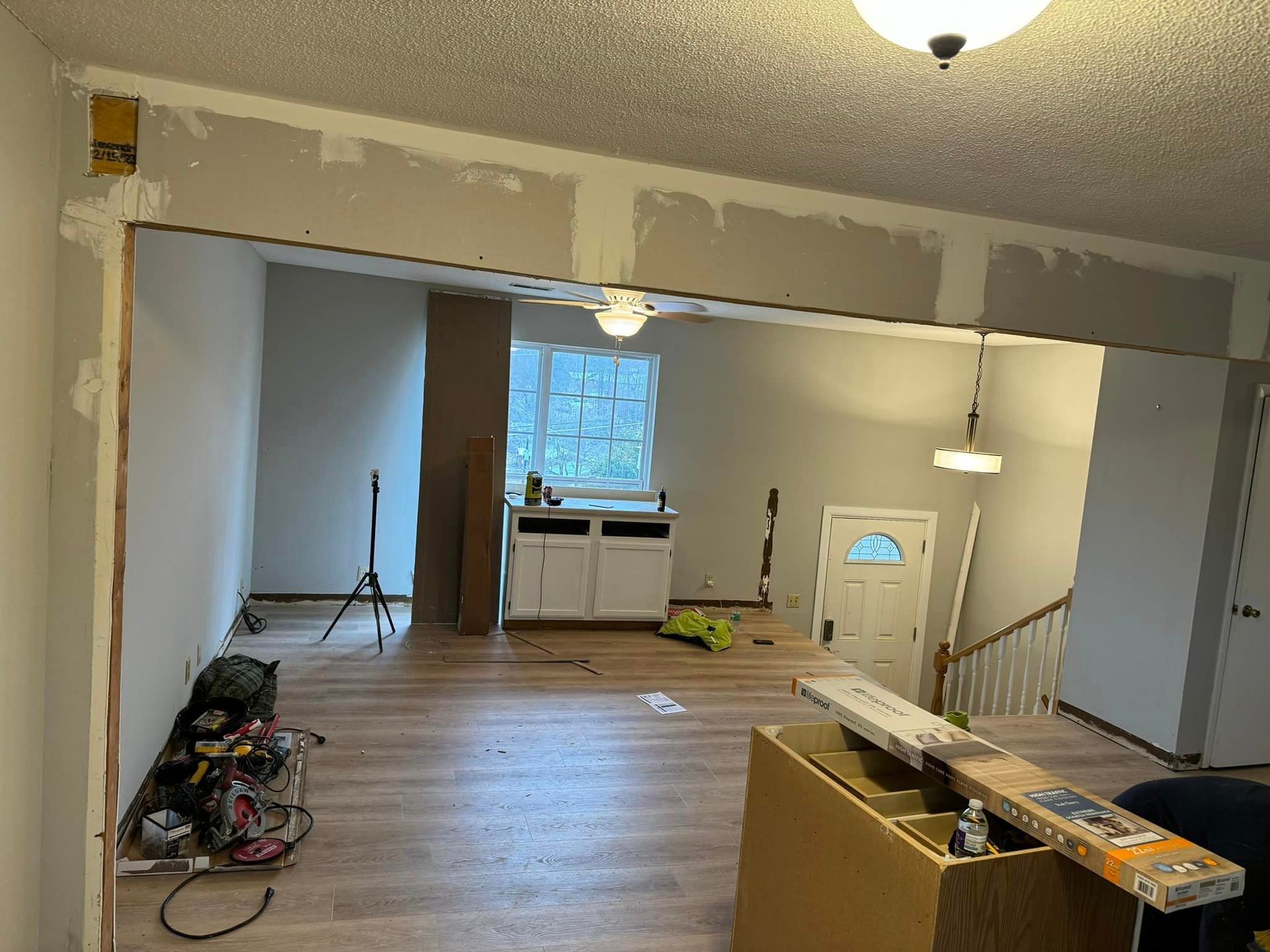 A living room with a ceiling fan and a door being installed.
