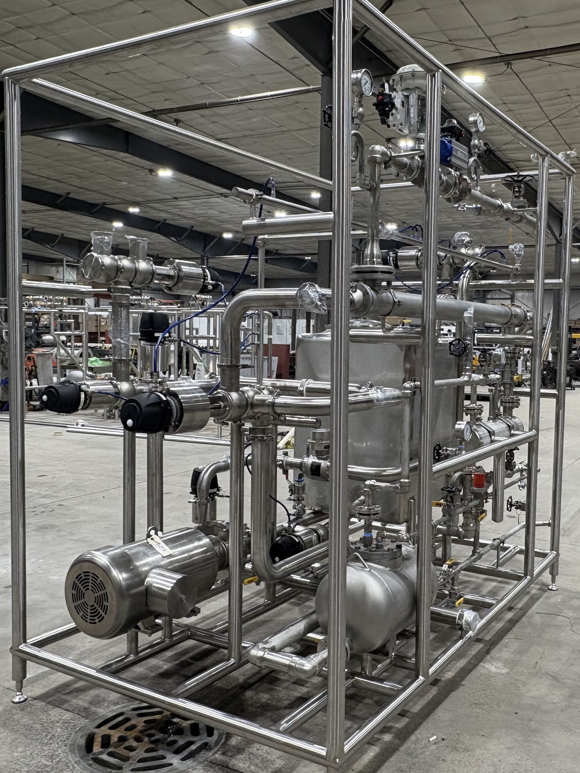 Stainless steel industrial equipment on a steel frame, likely for processing liquids in a factory setting.