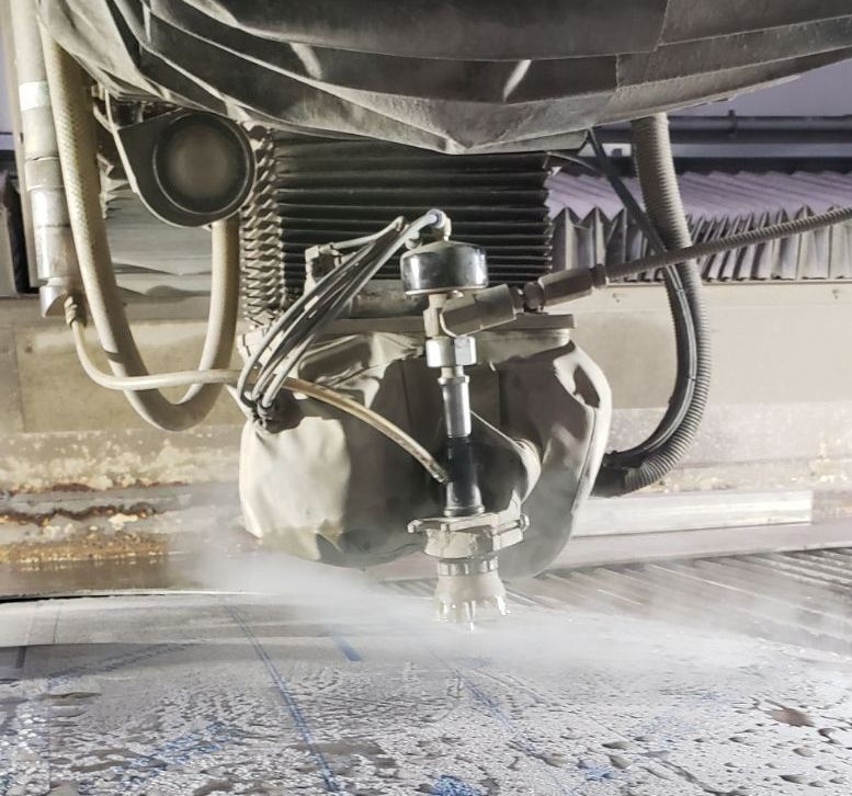 Water jet cutter in action, spraying water on a surface with visible mist.