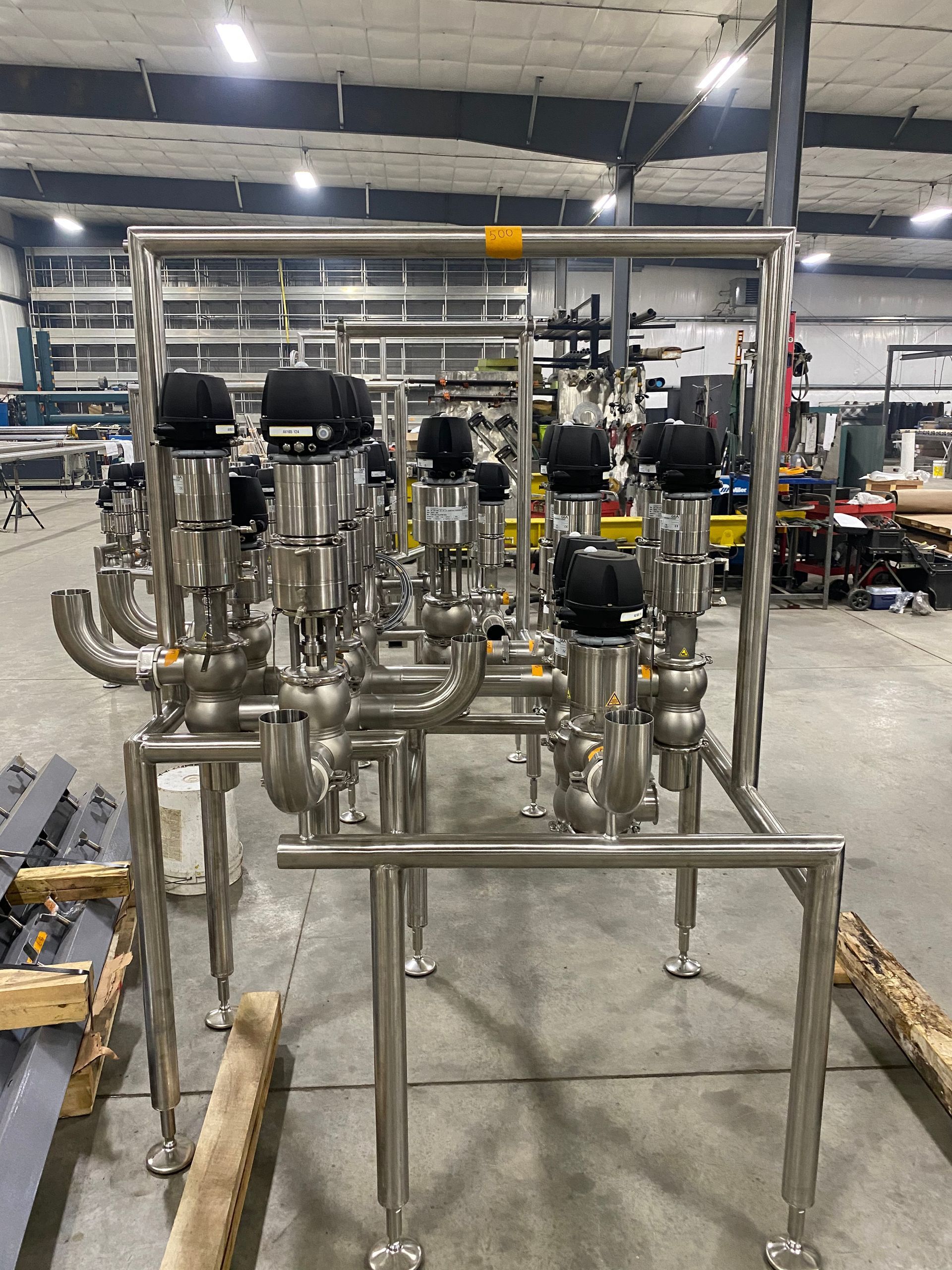 Stainless steel process piping assembly with actuated valves, in an industrial setting.