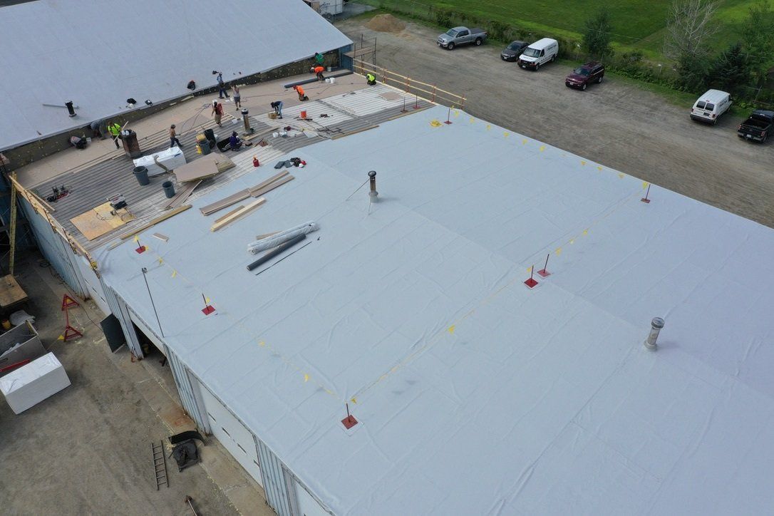 Ongoing Industrial Metal Roof Retrofit with workers and equipment on the expansive site.”