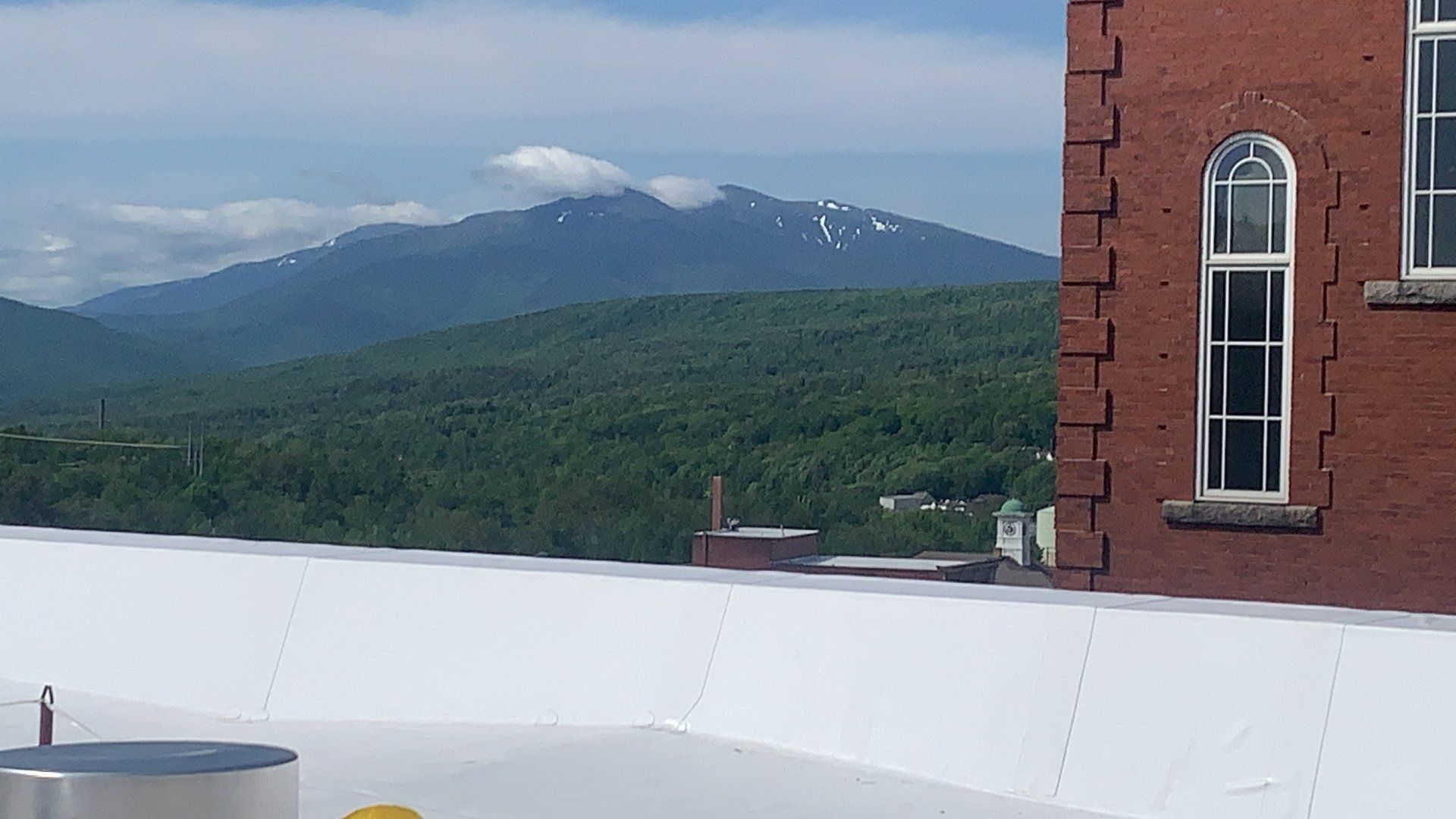 A brick building with a white roof and mountains in the background