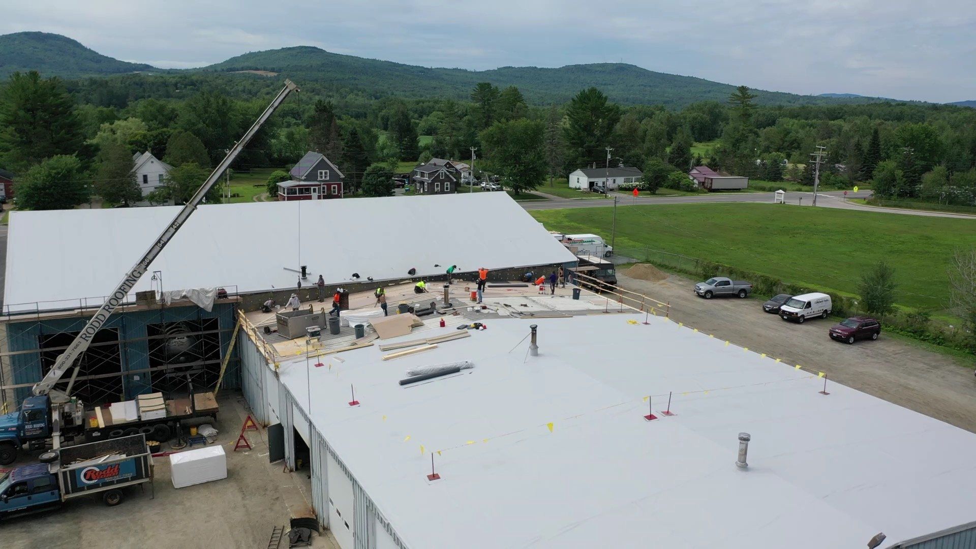 Large-scale Metal Roof Retrofit in progress, with workers and materials atop a commercial building.