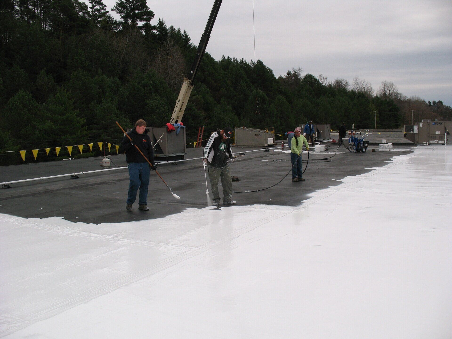 A group of people are working on a roof with a crane in the background