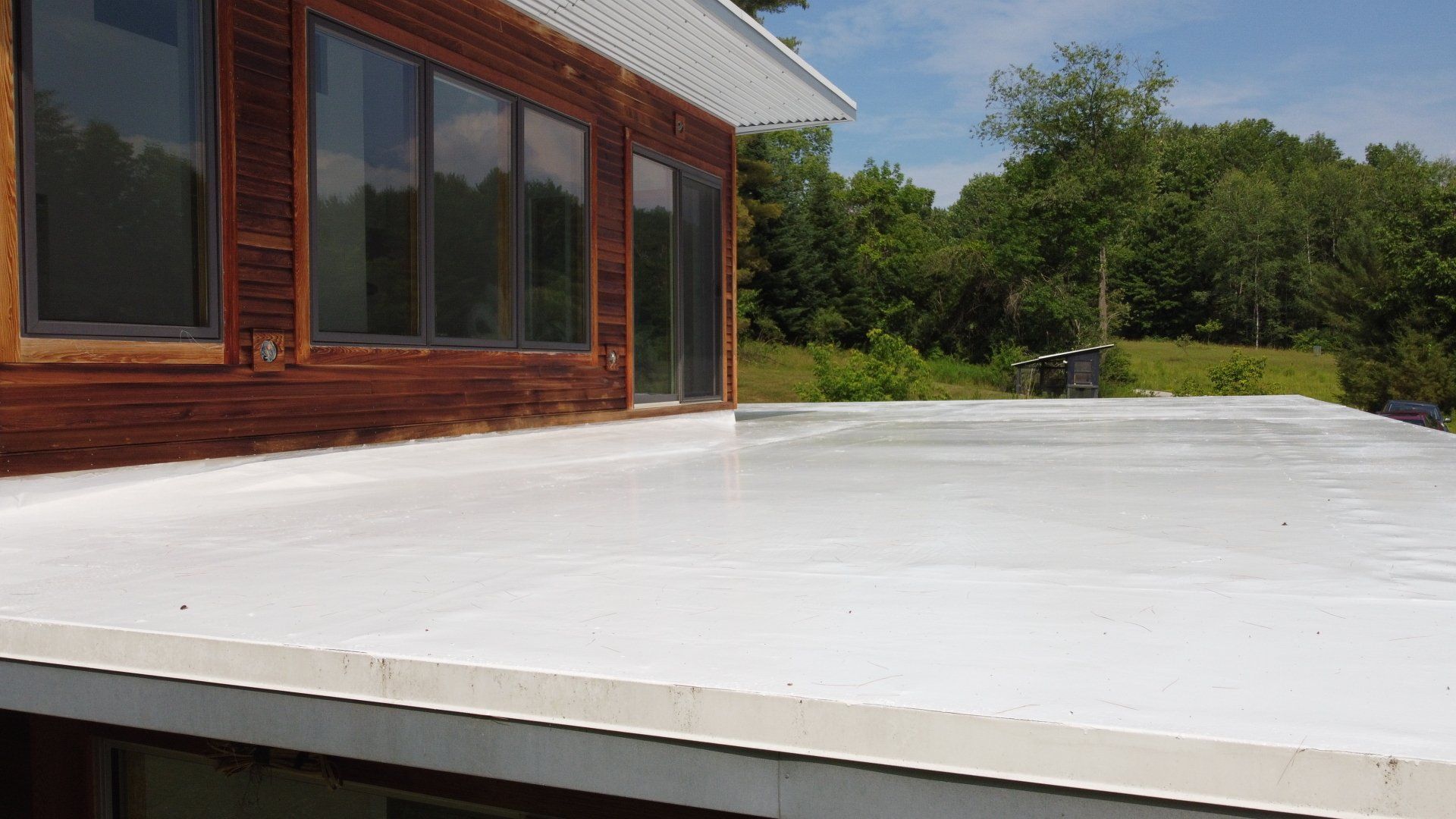 A white roof is sitting on top of a wooden house.