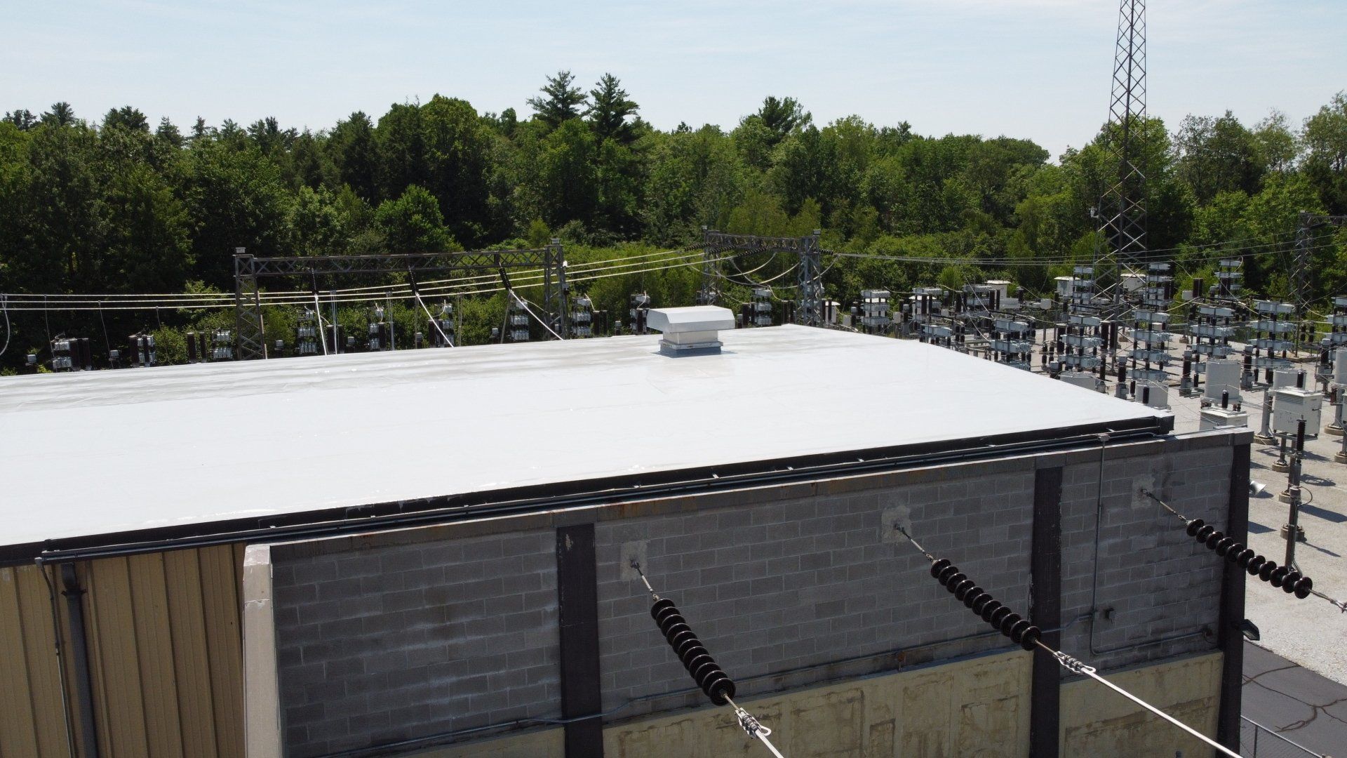 An aerial view of a building with a white roof and trees in the background.