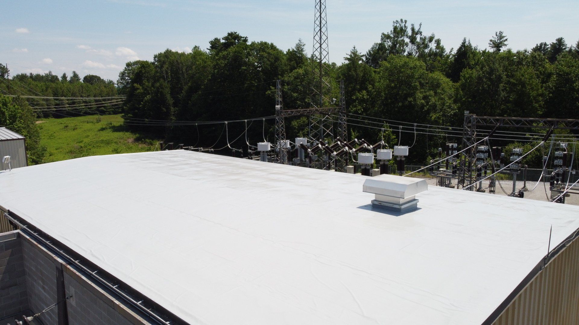 An aerial view of a white roof of a building with trees in the background.