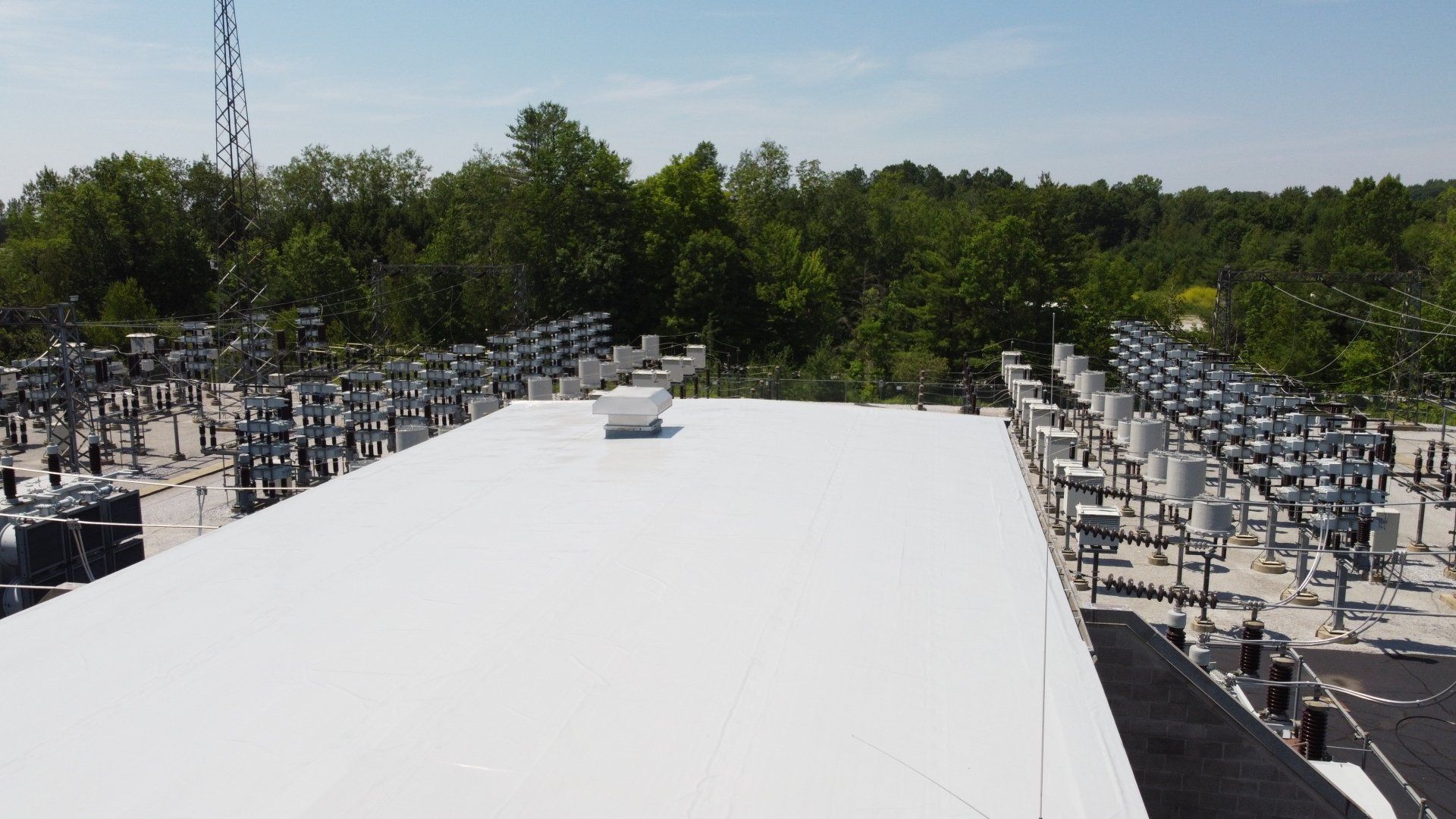 A large white roof with a lot of trees in the background.