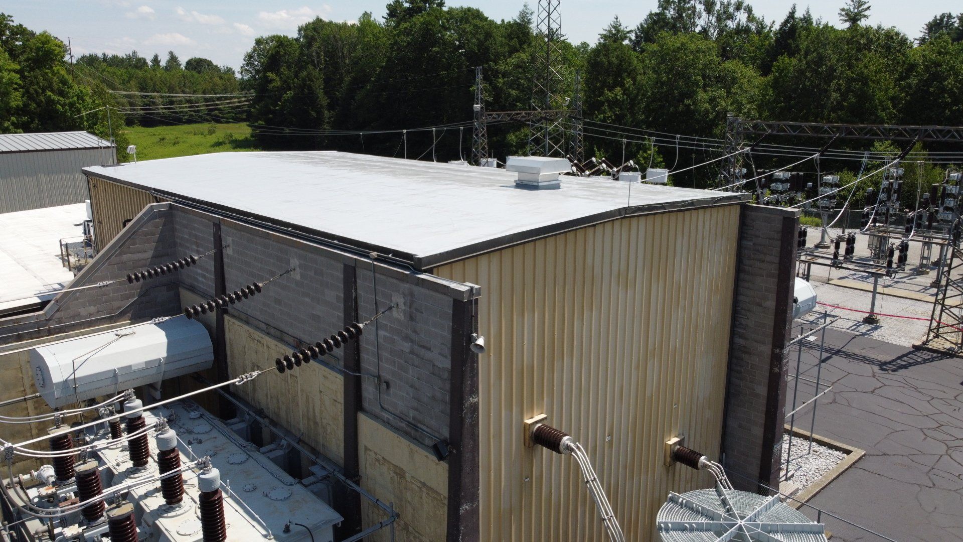 An aerial view of a large building with a white roof surrounded by trees.