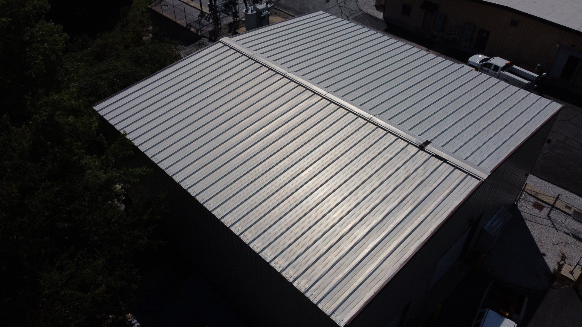 An aerial view of a metal roof of a building with trees in the background.