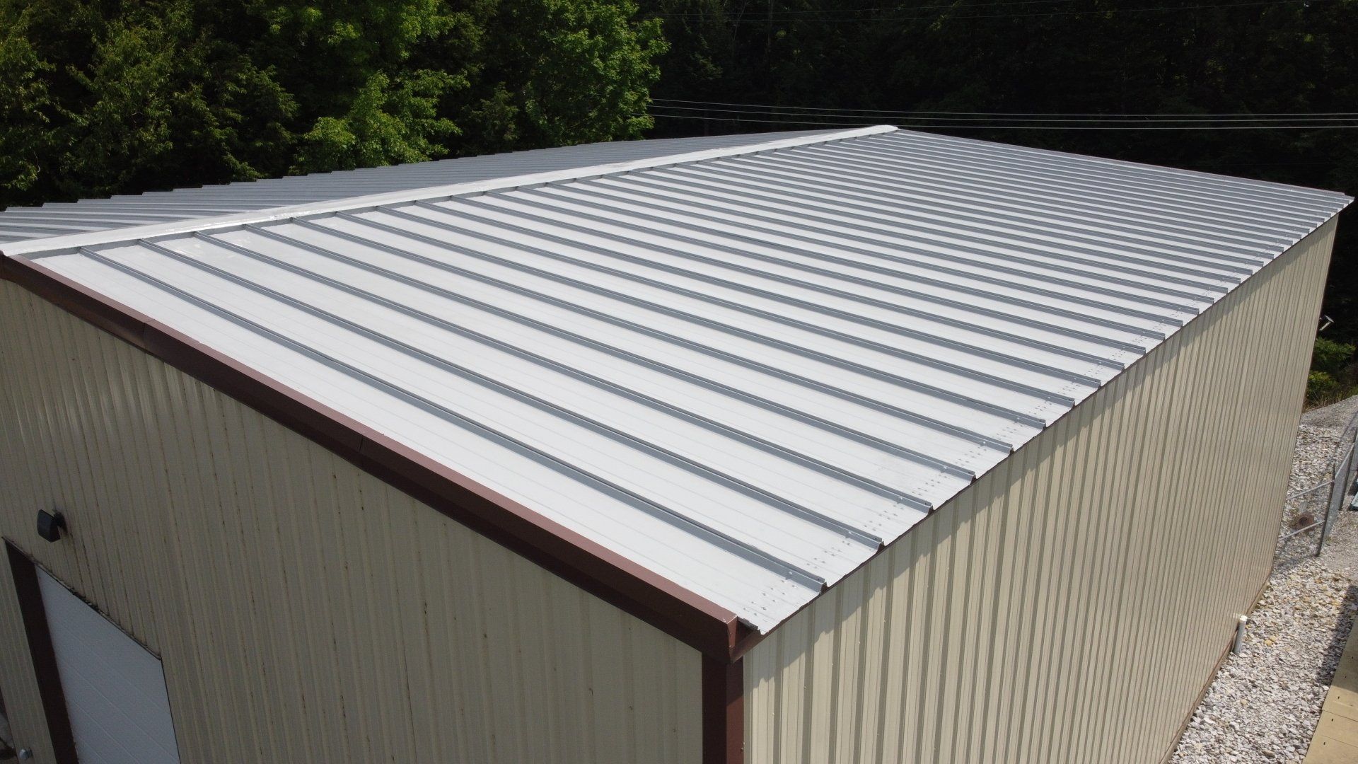 An aerial view of a metal building with a white roof.