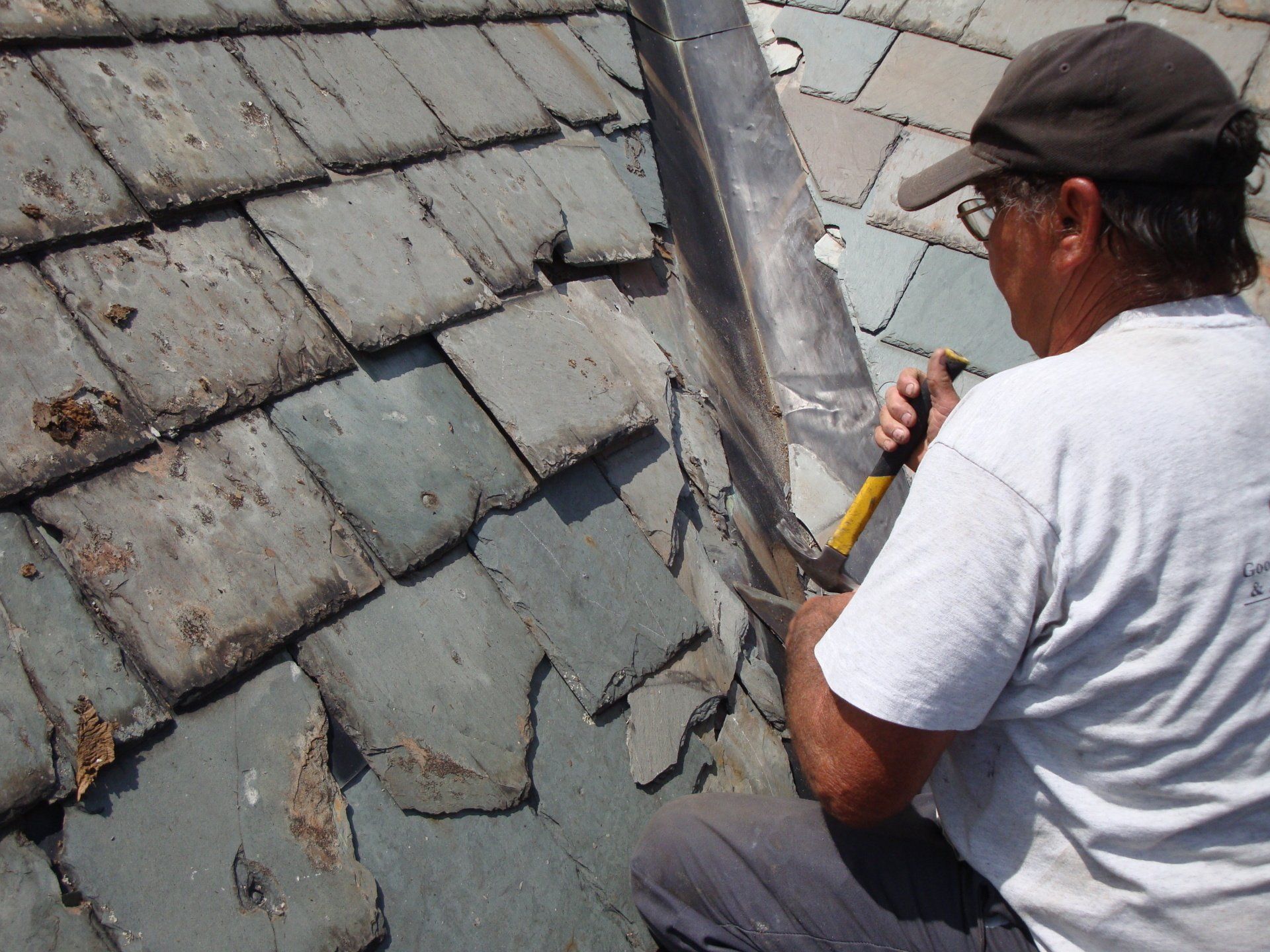 A man is working on a roof with a hammer