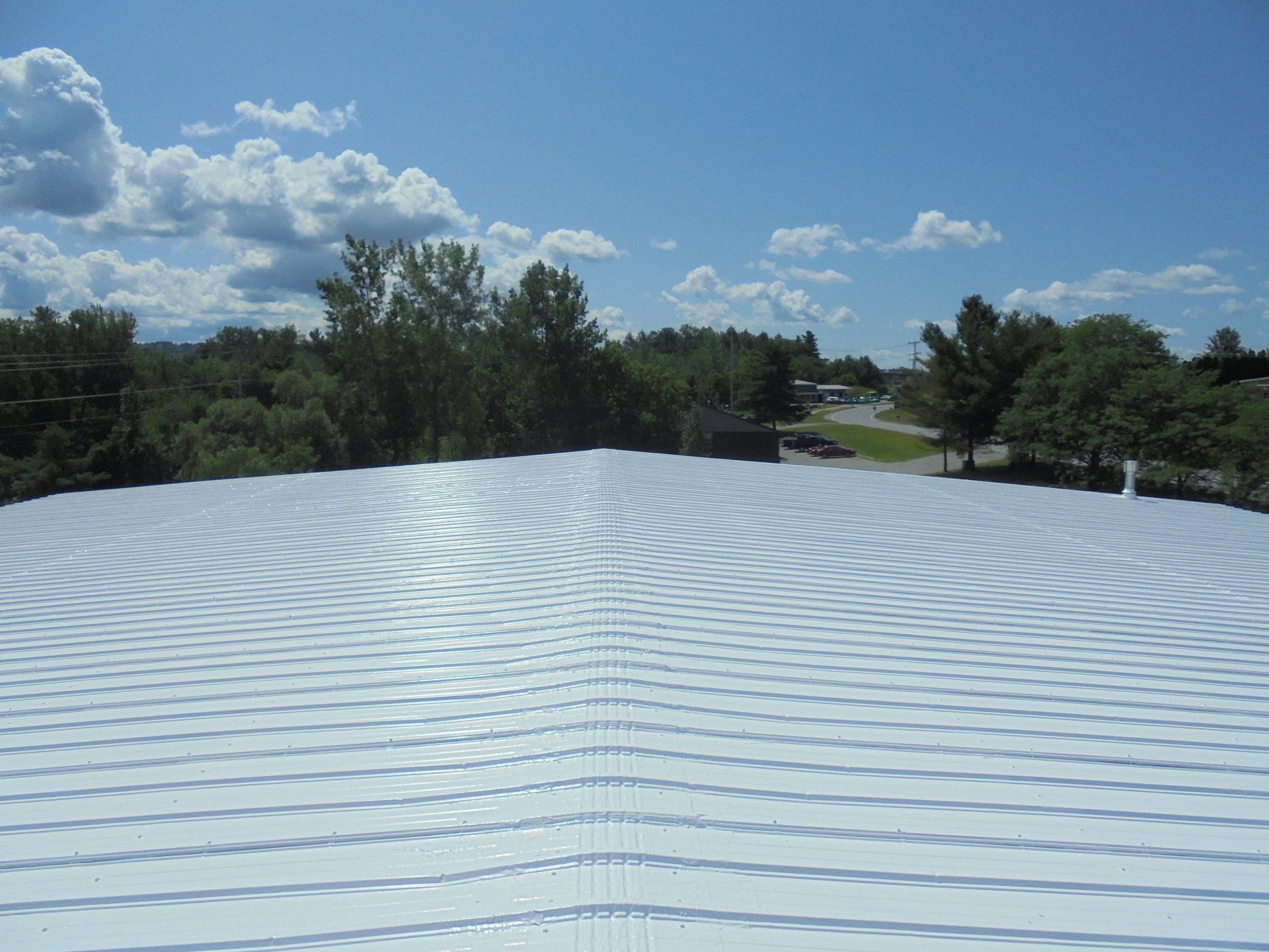 A white roof with a blue sky and trees in the background