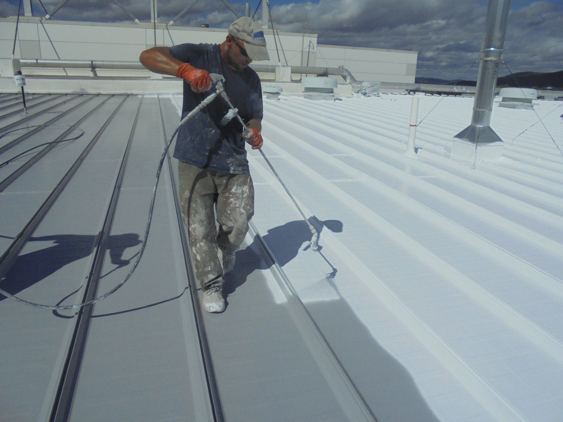 A Rodd Roofing expert painting liquid-applied roofing membrane on a commercial roof 