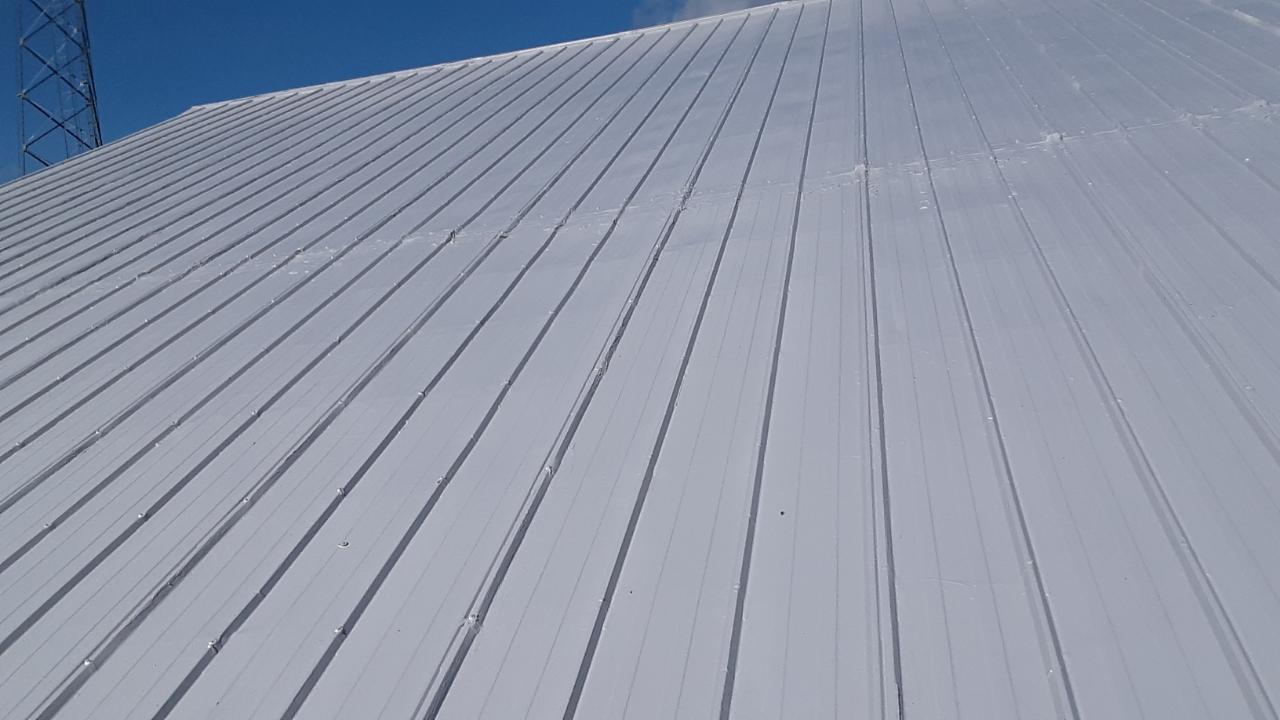 A close up of a white roof with a blue sky in the background.