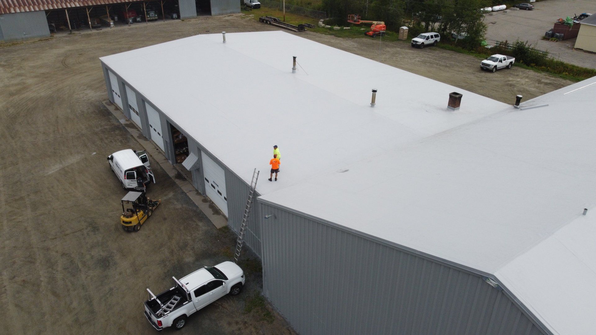 Rodd Roofing’s metal retrofit project with a worker on top, highlighting industrial roofing expertise.