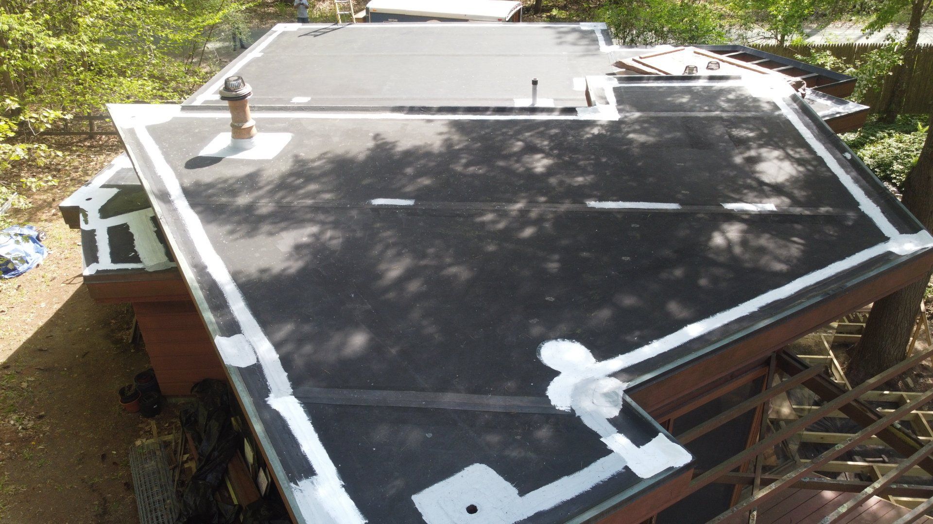 A black roof with white lines on it is sitting on top of a house.