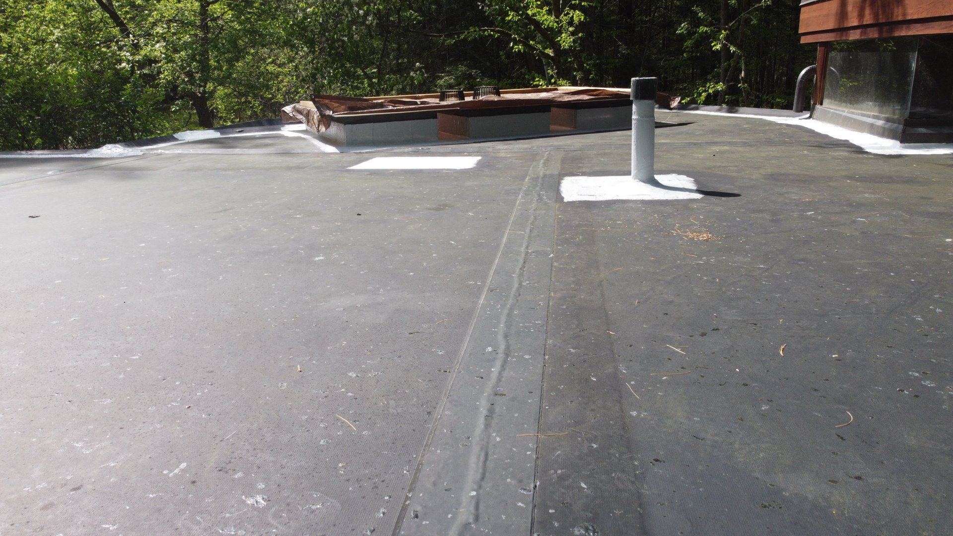 A roof with a chimney on it and trees in the background