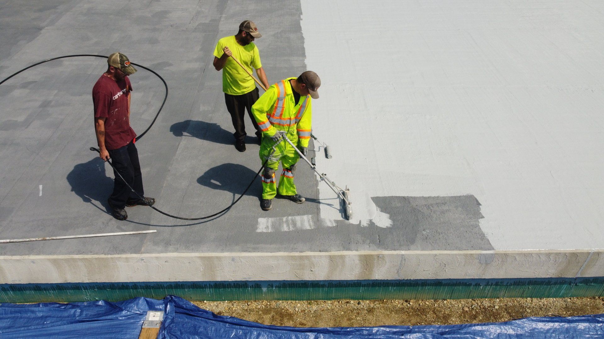 Rodd Roofing experts painting a commercial roof with liquid-applied roofing membrane.