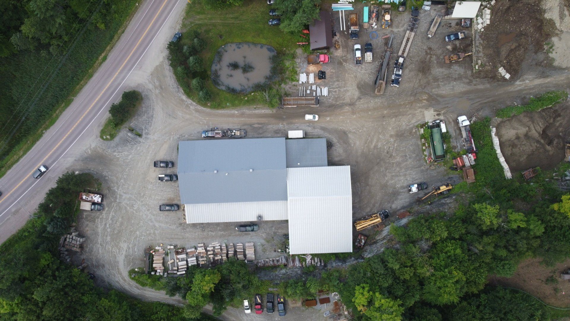 An aerial view of a large building surrounded by trees and a road.