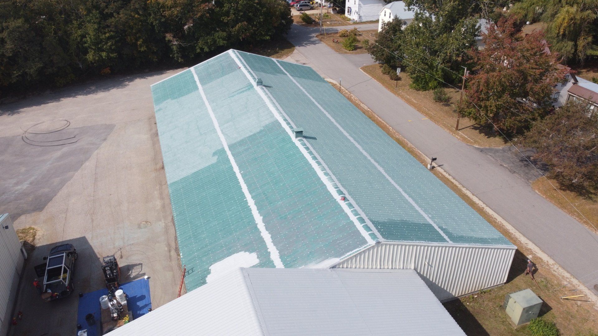 An aerial view of a large building with a green roof being painted.