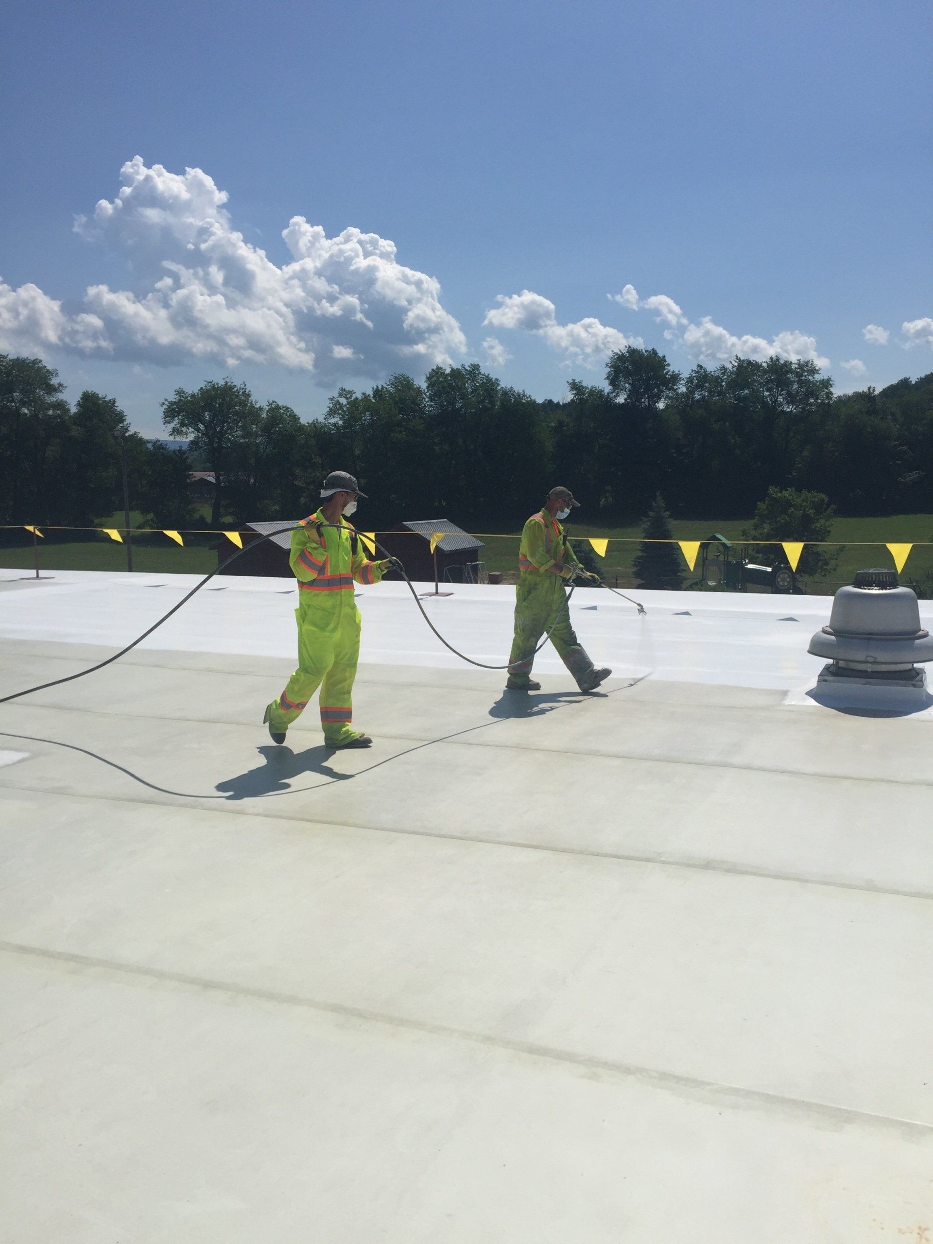Two roofers from Rodd Roofing work on a commercial flat roof in Vermont