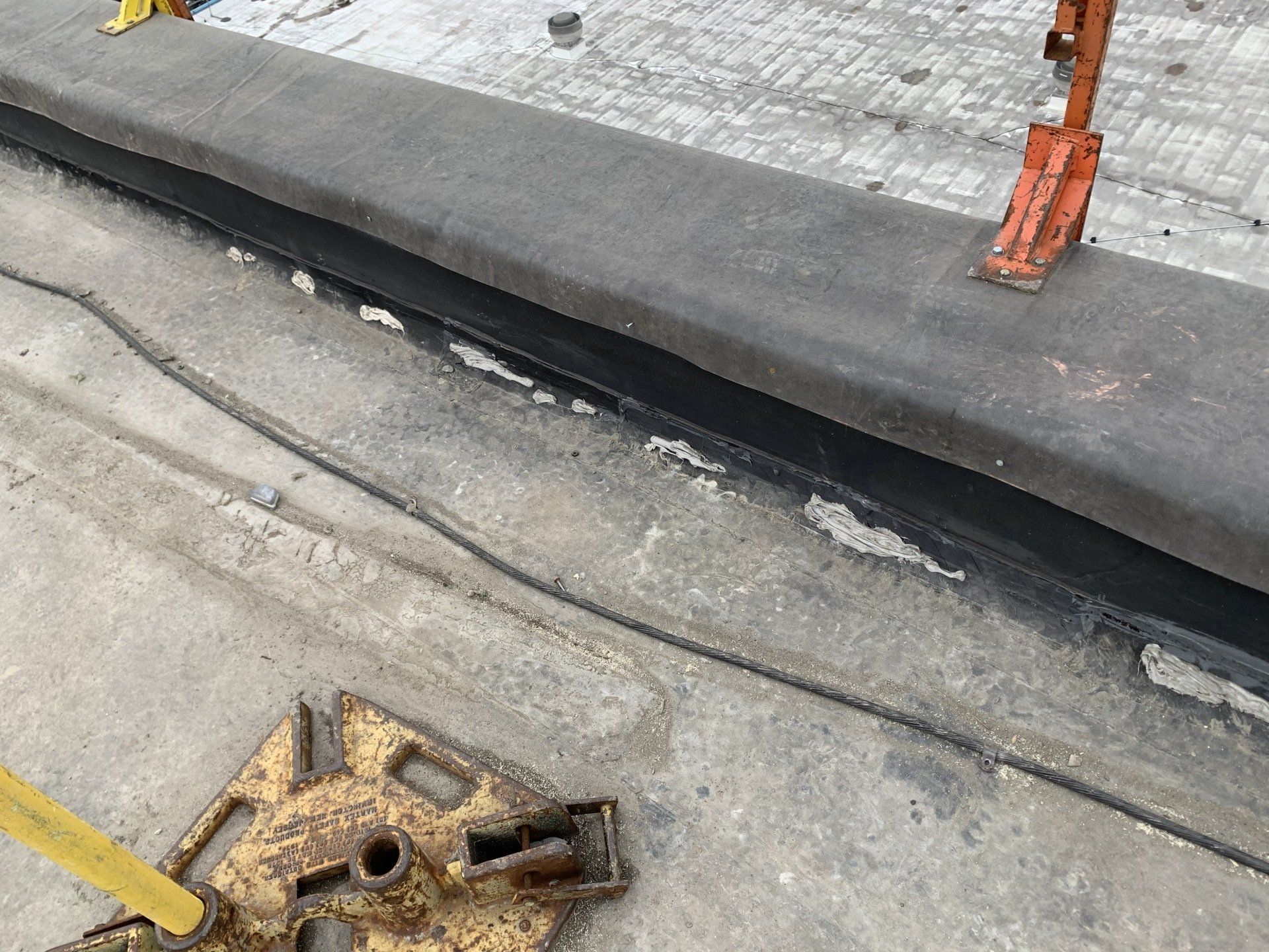 A yellow object is sitting on the ground next to a concrete surface.