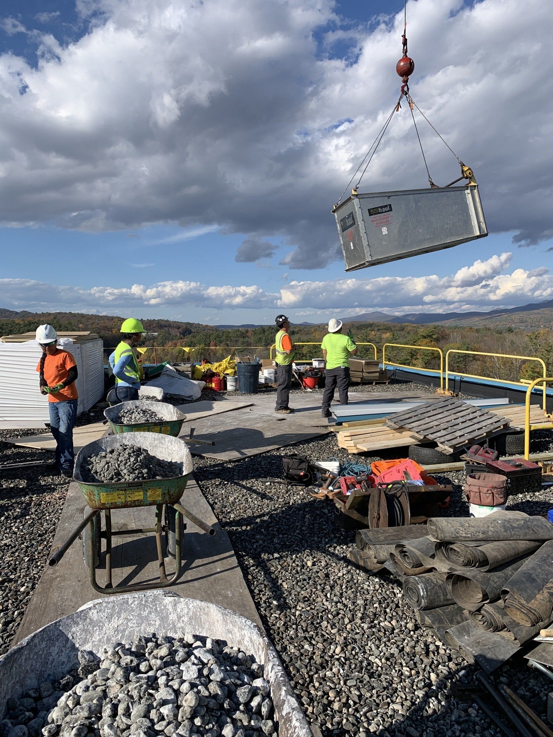 A large container is being lifted by a crane on a construction site.