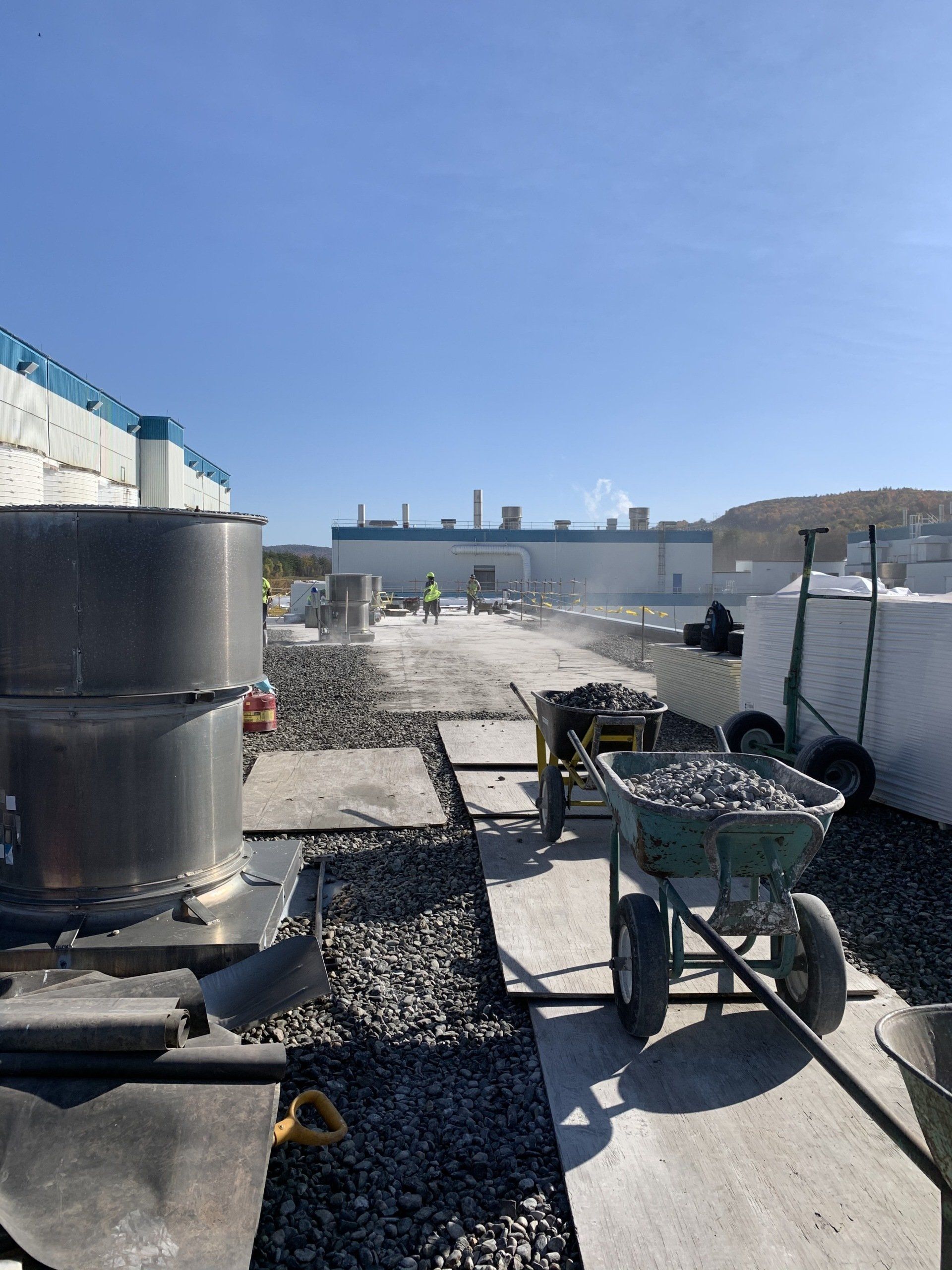 A wheelbarrow filled with gravel is parked in front of a large building.