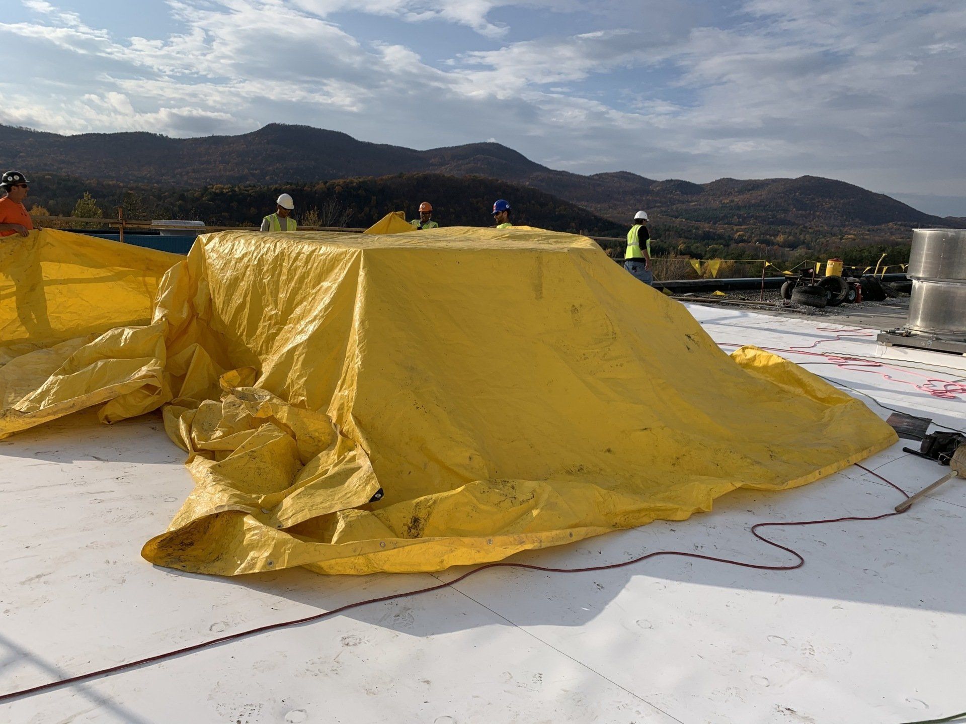 A large yellow tarp is sitting on top of a white roof.
