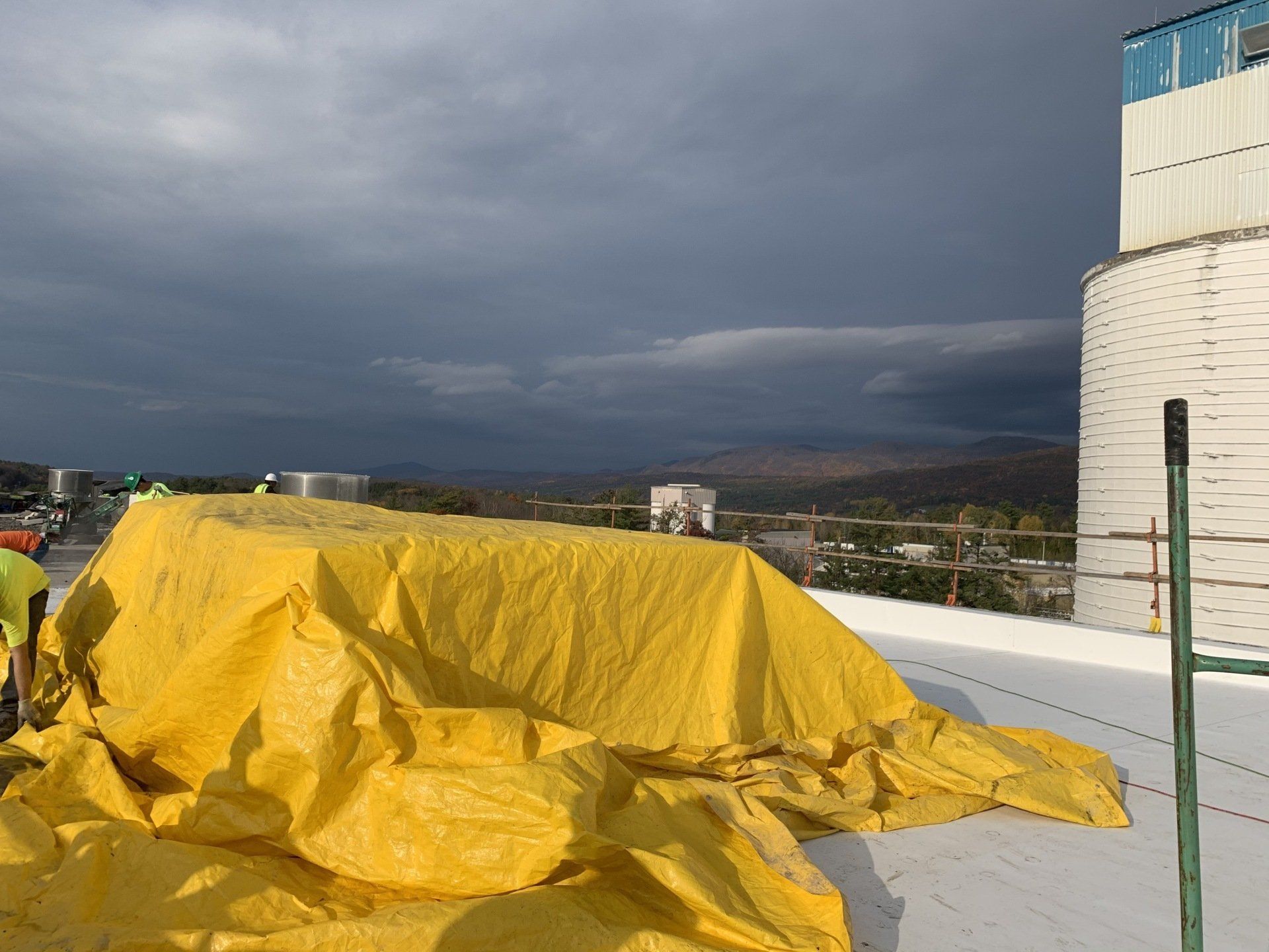 A large yellow tarp is sitting on top of a white roof.